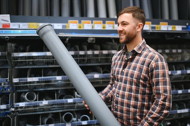 handsome workman choosing sewer pipes standing near showcase plumbing shop 255667 78177